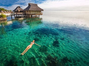 Woman in white bikini swimming in coral lagoon, Moorea, Tahiti