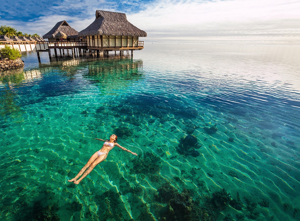 Woman in white bikini swimming in coral lagoon, Moorea, Tahiti
