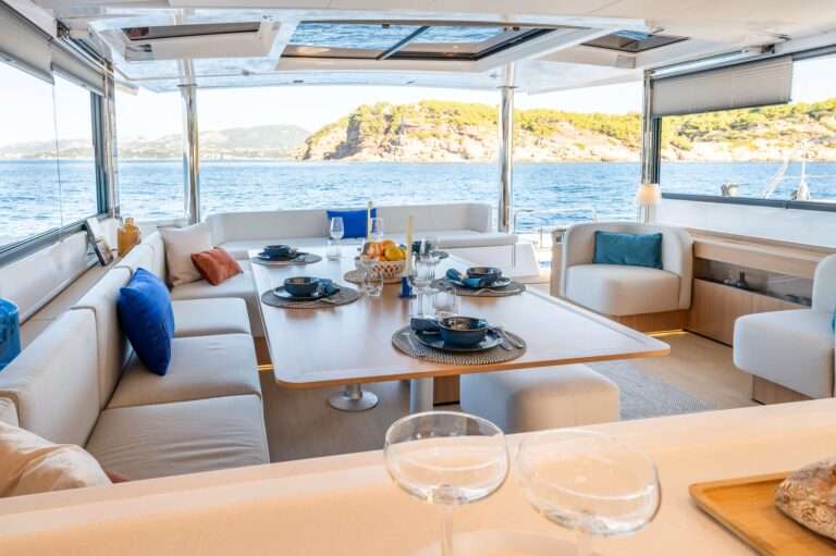 Catamaran BALI 58 Table du carre dressee avec porte basculante ouverte sur la mer