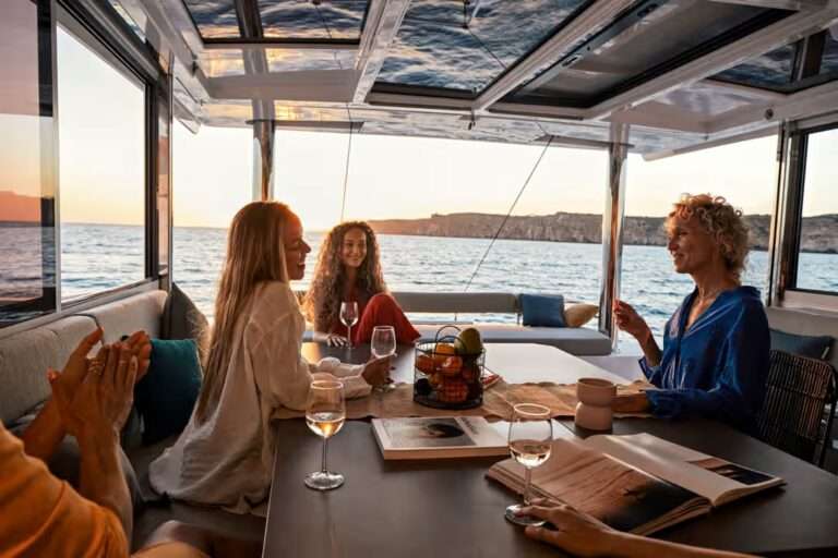 Catamaran BALI Femmes buvant du vin sur la table du carre au coucher de soleil